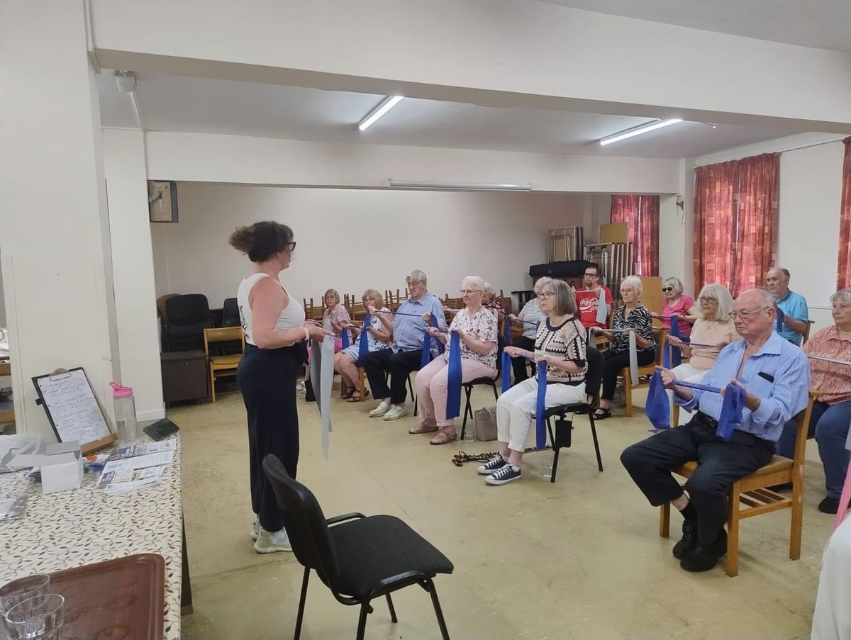 Julie leading a seated resistance band exercise with Breaston Evergreens members